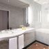 Living Hotel an der Oper, Vienna bathroom with marble walls, bathtub, glass shower, and double sink