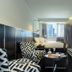 NYX Tel Aviv guest room with city view, bed by window, patterned chairs and black-and-white decor