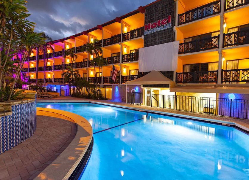 The Garden Hotel & Resort in Fort Lauderdale with illuminated pool and palm-lined exterior at dusk