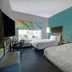 Tru by Hilton Austin Airport room with two beds, desk, window view, and teal accent wall in Austin
