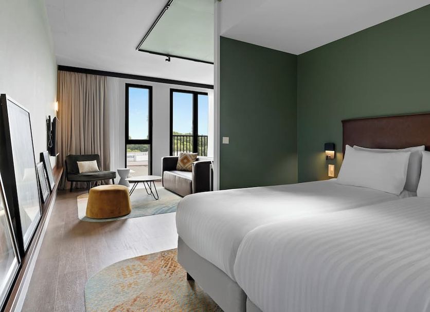 Corendon Urban Amsterdam Schiphol Airport Hotel in Badhoevedorp: modern guest room with bed, seating area and large windows