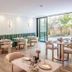Sovn Experience+Lifestyle Cape Town dining area with green banquettes and tables by an open glass wall