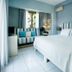 Kenta Beach Hotel in Agios Ioannis guest room with striped bed, window seat, and sea-view window