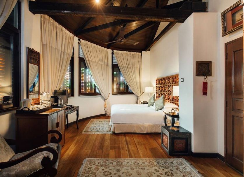 Campbell House in George Town guest room with wooden floor, canopy bed, curtains, and lounge chair
