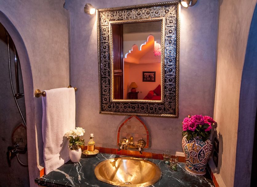 Riad Eden Marrakech bathroom with ornate mirror, copper sink, and arched doorway
