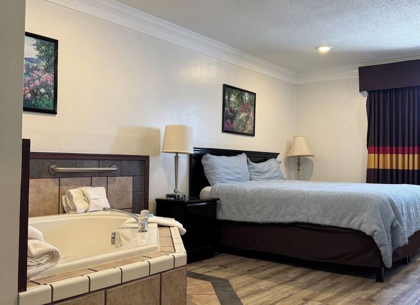 Home Suites Thief River Falls guest room with bed, jacuzzi tub, and bedside lamps