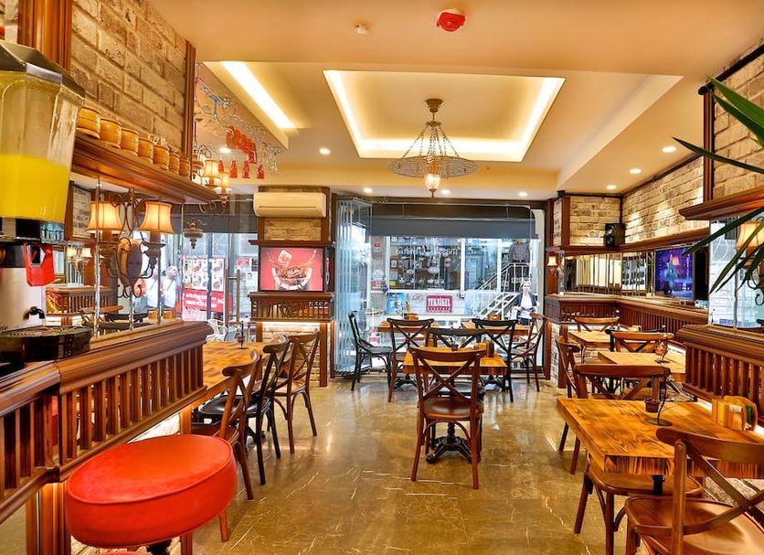 Anthemis Hotel Istanbul dining area with wooden tables, bar seating and large front windows