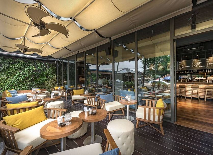 Hotel G Yangon outdoor terrace seating beside glass-walled bar with canopy in Yangon