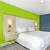 Signature Inn Berkeley guest room with white bed, lime green wall and blue accent wall in Berkeley