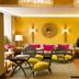 Hôtel Baume in Paris lounge with yellow walls, patterned sofa, woven chairs and round wall mirror