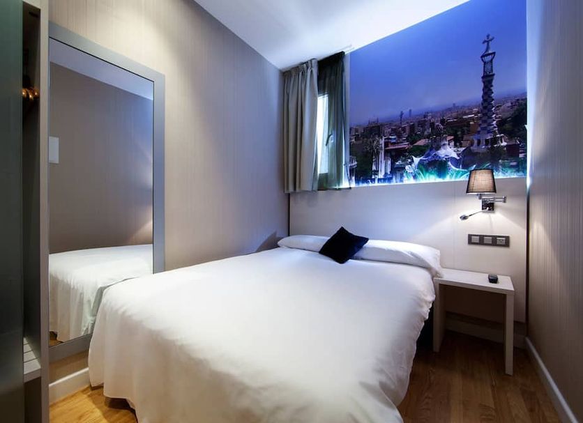 Hostal BCN Ramblas room in Barcelona with a single bed, wall mirror, and cityscape wall art