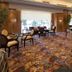Aston Manado Hotel in Manado lounge with patterned carpet, tables, and chairs beside large windows