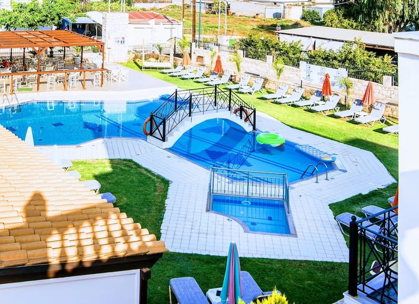 Yiannis Manos Hotel Resort in Mália with outdoor pool, sun loungers and a small bridge over the water