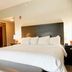 Hampton Inn Crystal River guest room with king bed, bench, armchair, and bedside lamps
