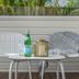 Cove Studios Byron Bay patio seating with two chairs, a small table, bottle and glass, and greenery beyond