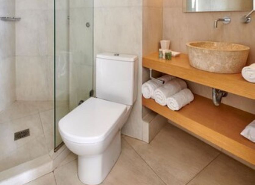 The Windmill Kimolos bathroom with walk-in shower, toilet, wood vanity and vessel sink in Kimolos