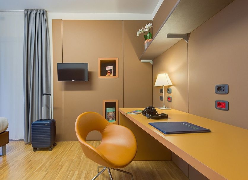 Camplus Bononia Casa Per Ferie in Bologna guest room with desk, chair, wall TV and window curtains