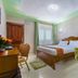 Kilimo Grand Resort Nairobi guest room with wooden bed, green chairs, desk and window curtains