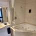 U Studios Paraparaumu bathroom with corner spa tub, glass shower screen, and vanity in Paraparaumu Beach