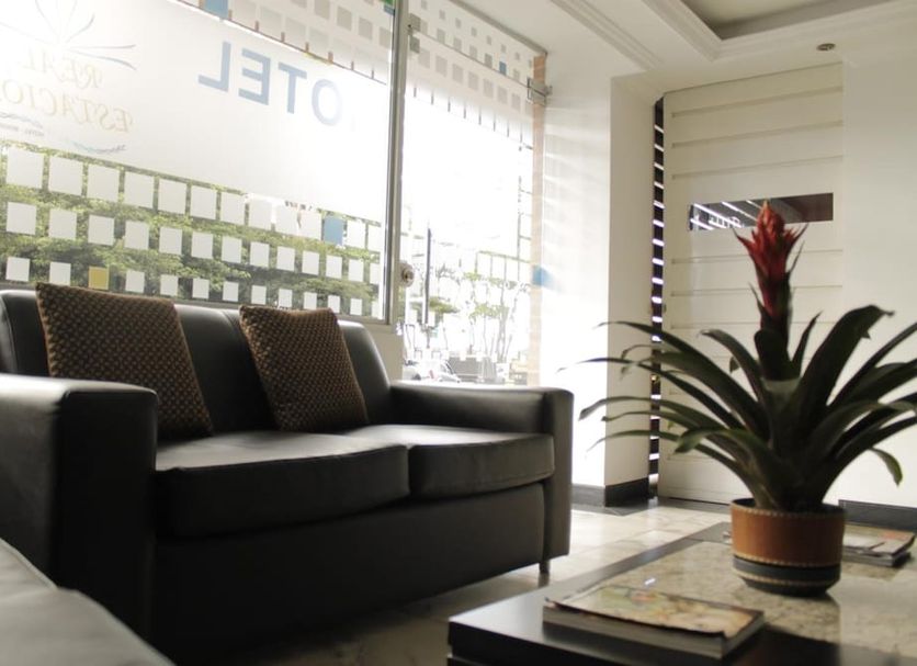Lobby seating area at Hotel Real Estación in Bogotá with black sofa and potted plant