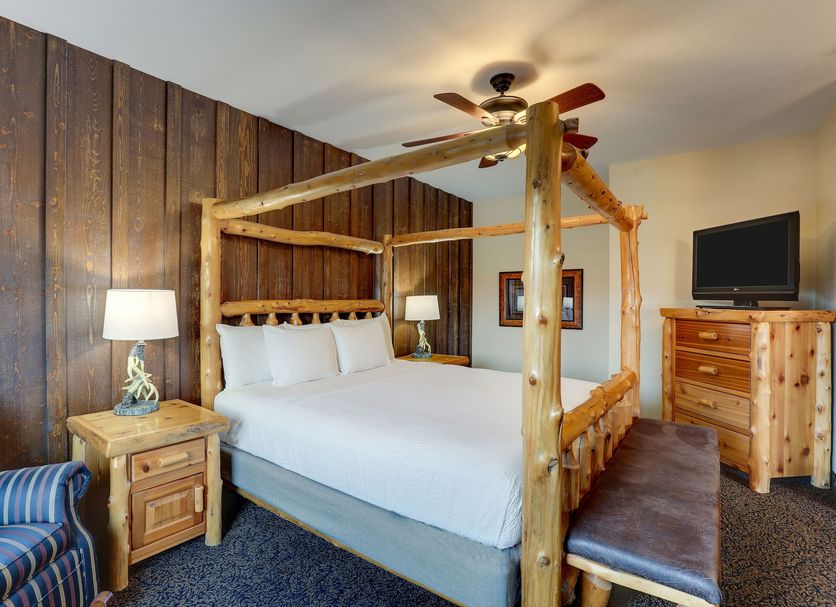 Stoney Creek Hotel Sioux City guest room with log four-poster bed, wood-paneled wall, and dresser in Sioux City
