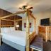 Stoney Creek Hotel Sioux City guest room with log four-poster bed, wood-paneled wall, and dresser in Sioux City