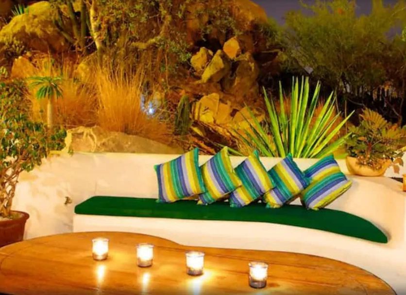 Los Milagros Hotel in Cabo San Lucas: white outdoor lounge with green bench, striped pillows, and candle-lit table