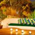 Los Milagros Hotel in Cabo San Lucas: white outdoor lounge with green bench, striped pillows, and candle-lit table