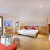 Familienhotel Mateera Gargellen room with double bed, red sofa, TV, and balcony in Montafon