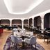 Hyatt Regency London Stratford dining room with round tables, red chairs and arched window seating