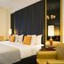 Melia Paris Champs Elysees guest room in Paris with king bed, gold chairs, tall curtains and bedside lamps