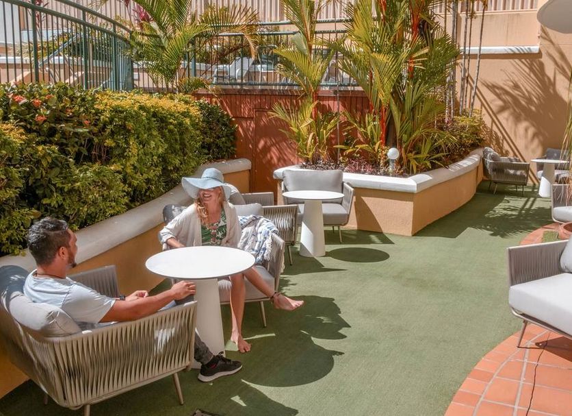 Il Palazzo Holiday Apartments Cairns outdoor courtyard seating with potted palms and lounge chairs
