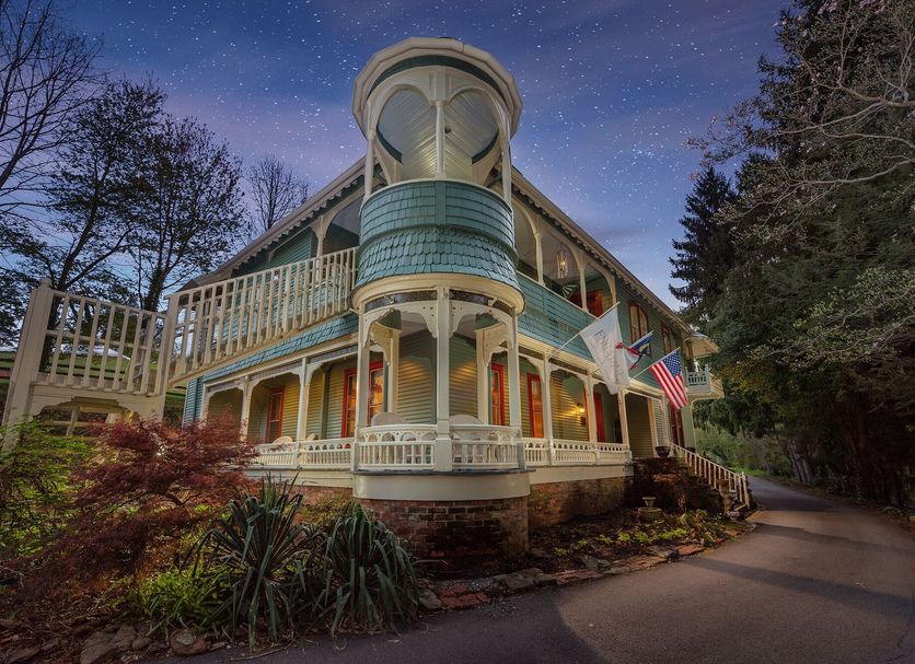 Engadine Inn and Cabins in Candler, Victorian-style inn exterior with wraparound porch at dusk