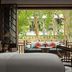 Rosewood Luang Prabang room with open doors to a leafy terrace and seating area in Luang Prabang