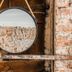 Mother Goose Hotel Utrecht: round mirror on rustic brick wall with wooden shelf