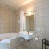 Finns Paekakariki bathroom with a jetted tub, wall-mounted sink, and tiled walls in Paekakariki