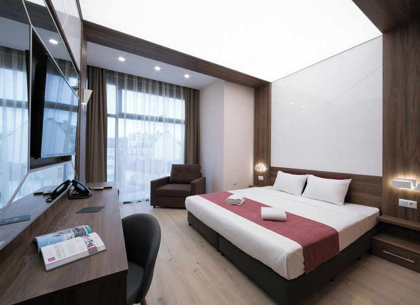 B1 Boutique Hotel Sofia in Sofia: modern guest room with king bed, desk, armchair, and large window