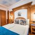 Chalet Mottolino Livigno bedroom with wood-paneled bed, blue throw, desk and wall mirror