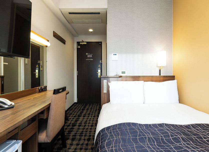 APA Hotel Toyama Ekimae Minami in Toyama: compact room with bed, desk, chair, and entry door