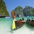 Nadivana Serviced Apartment in Krabi with longtail boats on a turquoise beach and limestone cliffs