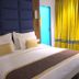 Sri Nanak Continental Hotel New Delhi guest room with king bed, blue headboard, and yellow curtains