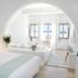 Aqua Blue Beach Hotel in Perissa guest room with white bed and sea-view seating area