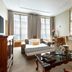 Meliá Paris Vendôme room in Paris with seating area, desk, fireplace and tall windows