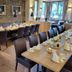Landhotel Ewerts in Nuerburg dining room with set tables, dark chairs, and stone accent wall