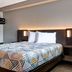 Studio 6-Jacksonville, FL - Baymeadows room with bed, nightstands, and geometric bedspread