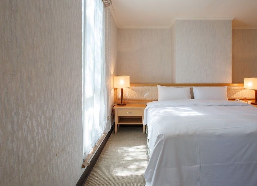 The Koos Hotel in Xindian District bedroom with a king bed, bedside lamps, and soft natural light