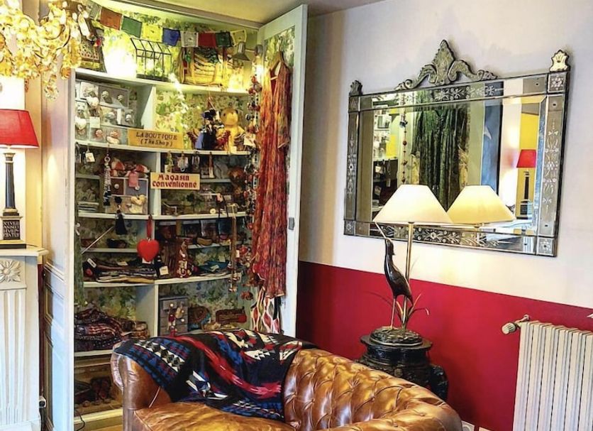La Cour Sainte Catherine in Honfleur: cozy lounge with leather sofa, mirror, lamp, and colorful shelves