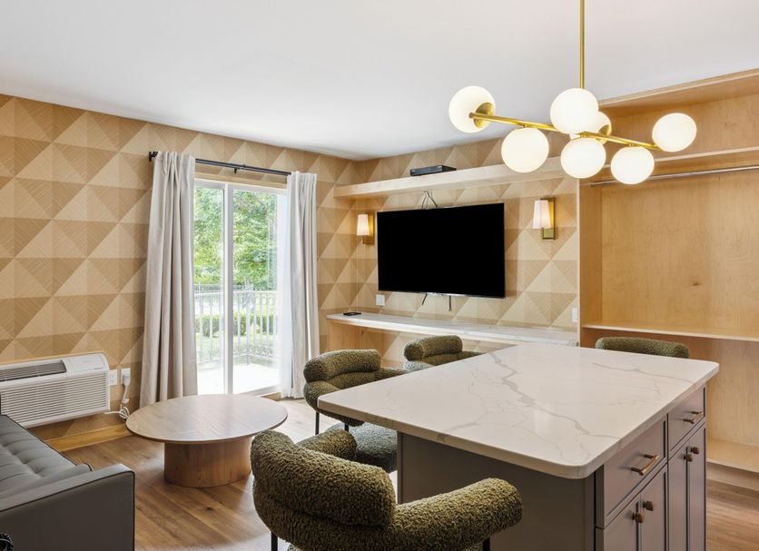 Greenview Inn Riverhead guest room with kitchenette, TV, seating area and sliding glass door