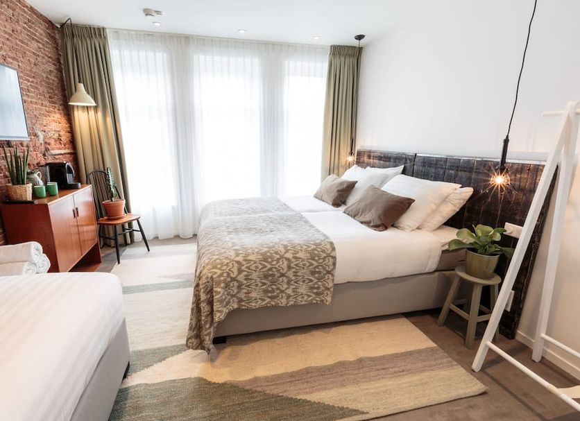 Hotel Dwars Amsterdam room with double bed, twin bed, brick accent wall and large windows