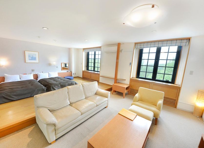 Colosseum Inn Tateshina guest room with sofa, two armchairs, and large windows in Tateshina